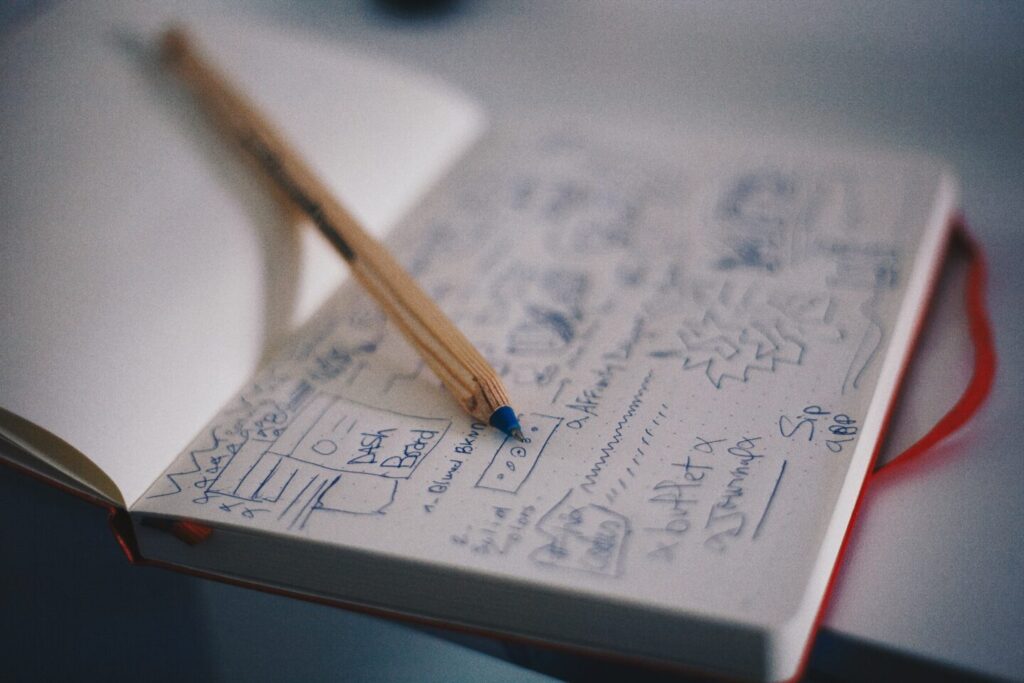 A notebook with sketches of a website design and the yellow pencil