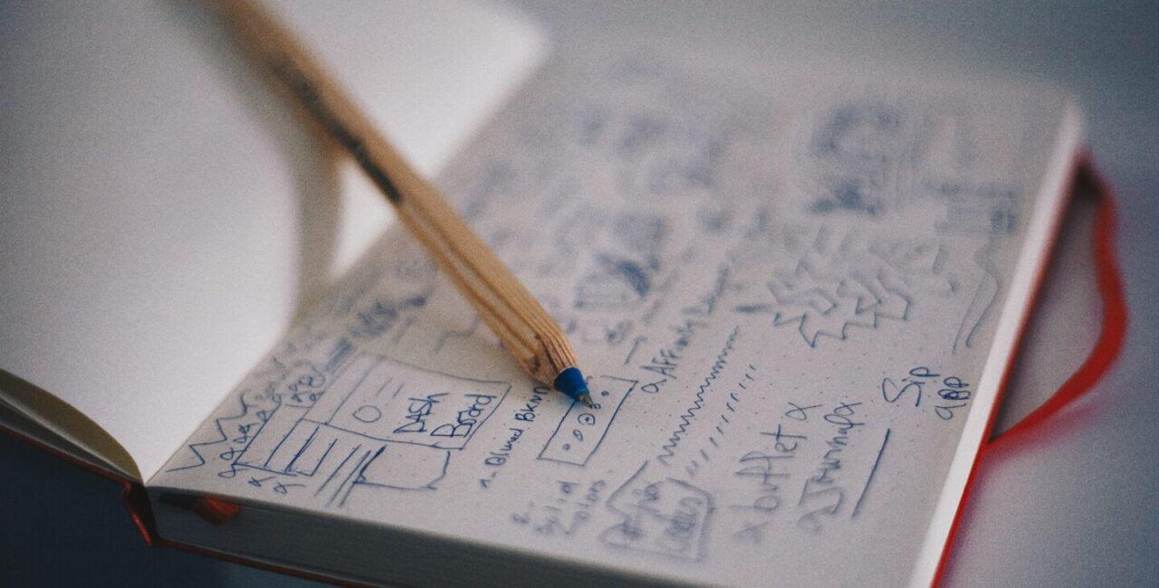 A notebook with sketches of a website design and the yellow pencil
