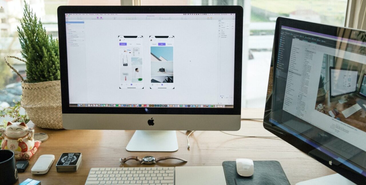 Two Apple monitors on a wood desk, magic keyboard help UX designer to create useful elements for websites