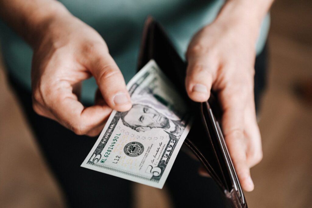 Somebody is taking five dollars out from a wallet
