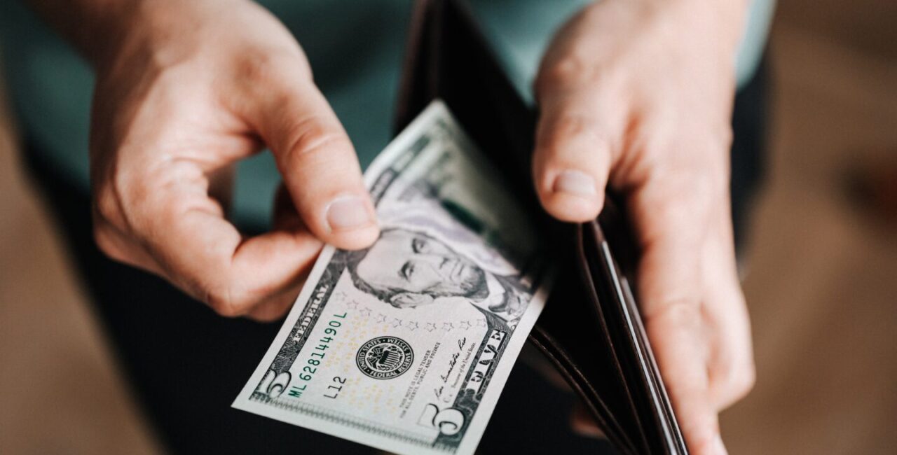 Somebody is taking five dollars out from a wallet