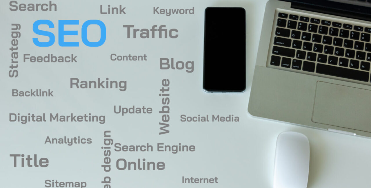 Top view laptop, smart phone and mouse are on the table. SEO and web text concepts on the table.