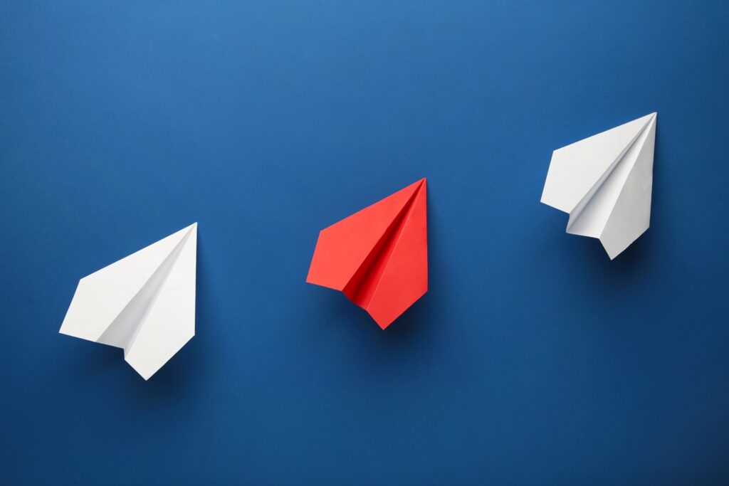 Color paper plane on dark blue background, Business competition concept. Top view