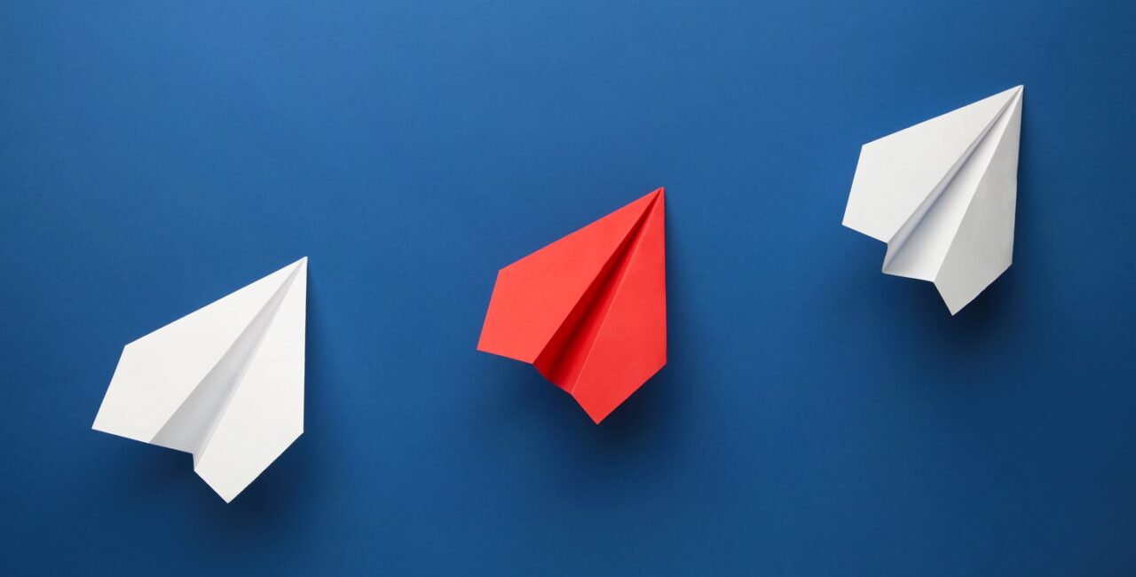 Color paper plane on dark blue background, Business competition concept. Top view