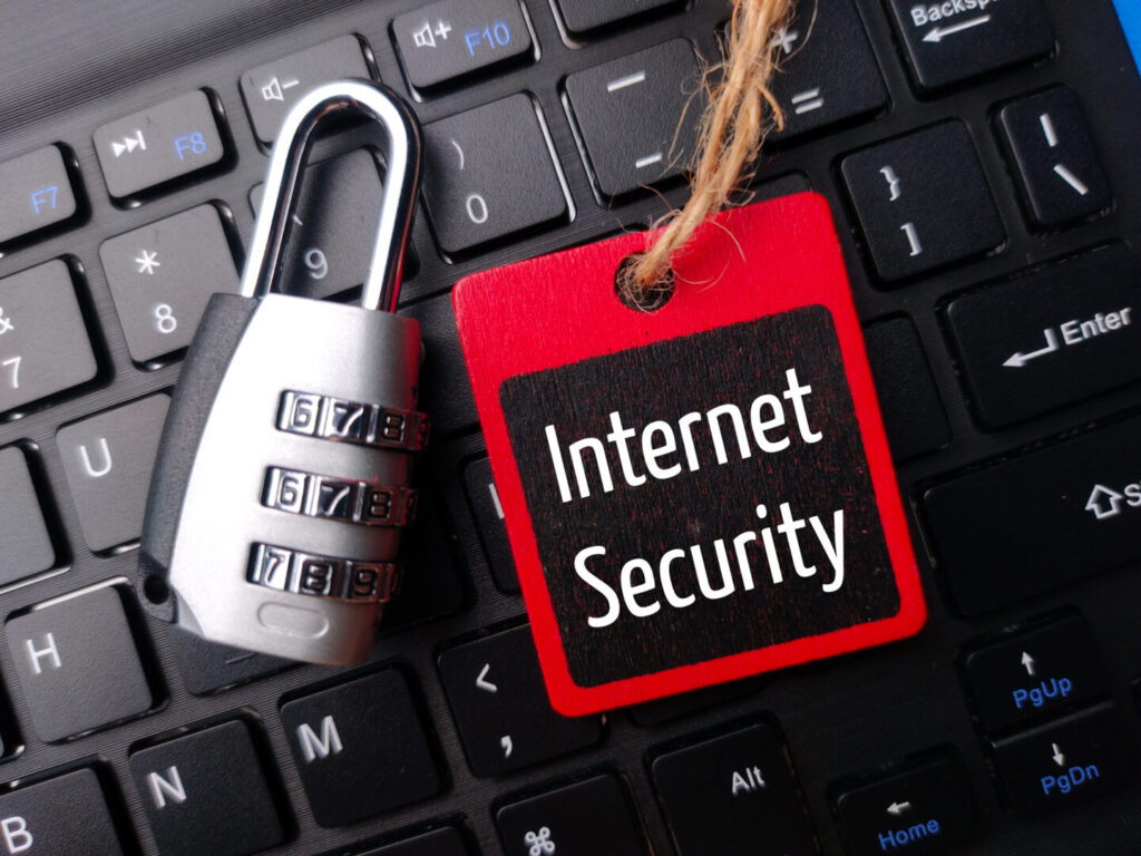 Padlock and wooden board with the word Internet Security on a wireless keyboard.