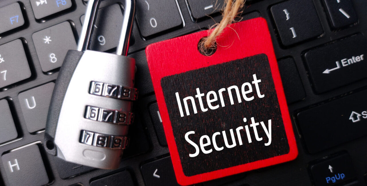Padlock and wooden board with the word Internet Security on a wireless keyboard.